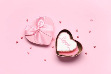 Kalp şeklinde kurabiyeler ve pembe arka planda dekor olan bir kutu. Sevgililer Günü kutlaması