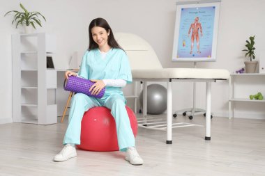 Rehabilitasyon merkezinde köpük silindirli kadın fizyoterapist.