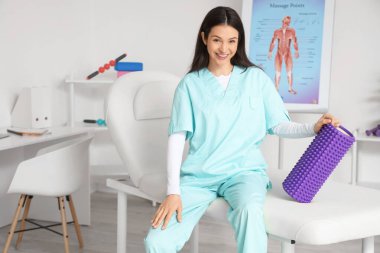 Rehabilitasyon merkezinde köpük silindirli kadın fizyoterapist.