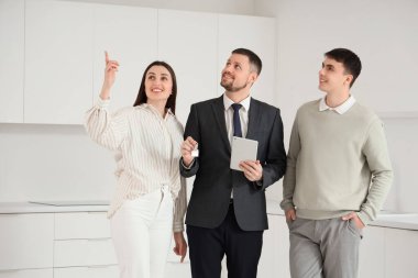 Tablet bilgisayarı olan bir emlakçı ve mutfakta bir çift.