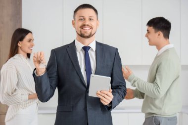 Tablet bilgisayarı ve anahtarı olan emlakçı mutfaktaki çifte karşı.