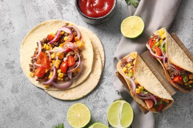 Gri arka planda lezzetli tacolar ve malzemeler.