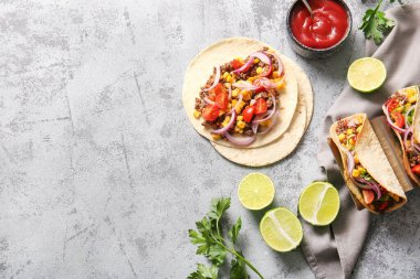 Gri arka planda lezzetli tacolar ve malzemeler.