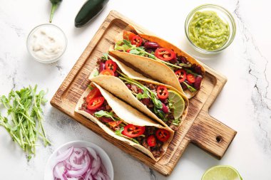 Tahta tepsi, beyaz mermer arka planda taze lezzetli tacolar.