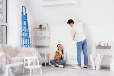 Pomeranya köpeği olan genç bir çift yeni evlerinin tamiri sırasında duvar kâğıdı yaptırıyor.