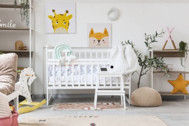 Çocuk odasının içinde, taburede beşik ve bebek monitörü var.