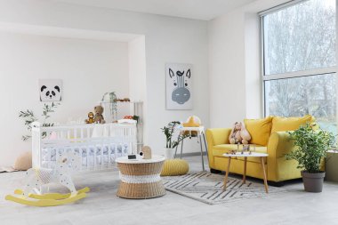 Kanepe, beşik ve bebek monitörlü bebek odası.