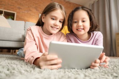 Evde tablet bilgisayarda çizgi film izleyen tatlı kızlar.
