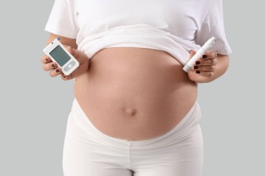 Glukometresi ve arka planda tükenmez kalemi olan hamile bir kadın, yakın plan. Gebelik Diyabet Konsepti