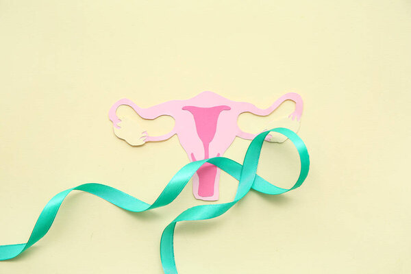 Turquoise ribbon with paper uterus on beige background. Cervical Health Awareness Month