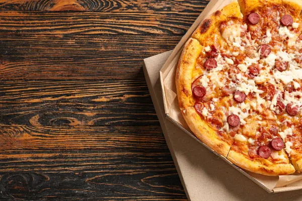 Tahta zemin üzerinde lezzetli pizzalar olan karton kutular.