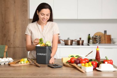 Mutfaktaki gübre için konteynıra yiyecek atan genç bir kadın.