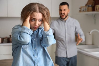 Yaralı genç kadın ve kızgın kocası mutfakta. Aile içi şiddet kavramı