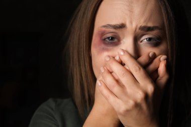 Siyah arka planda yaralı genç bir kadın, yakın plan. Aile içi şiddet kavramı