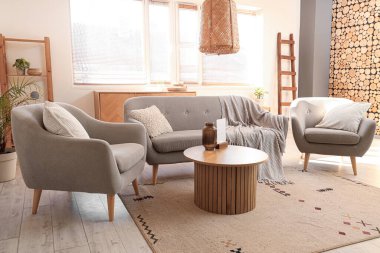 Rahat gri koltukları, kanepesi ve ahşap sehpası olan şık bir oturma odası.