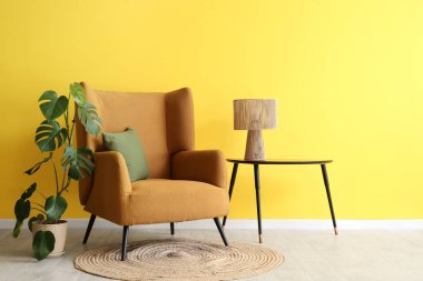 Kahve masasında rahat kahverengi koltuğu, çiçekleri ve lambası olan şık bir oturma odası.