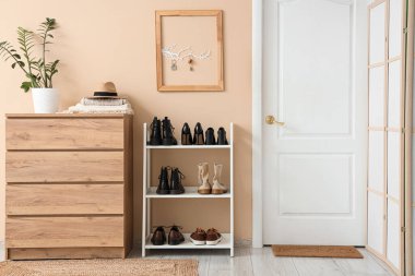 Çekmece, kapı, ayakkabı standı ve bej duvarda anahtar olan şık bir salon.