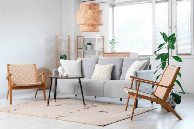 Şık, ahşap koltukları, modern gri kanepesi ve kahve masası olan bir oturma odası.