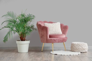 Şık bir oturma odası, rahat pembe koltuğu, çiçekleri ve puf.