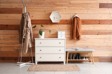 Şık bir salonun içinde çekmeceler, giysi askılığı ve ahşap duvarda anahtar tutacağı var.