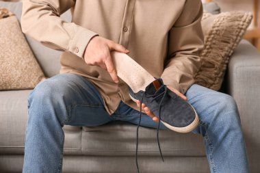 Genç adam evde ayakkabıya bej ortopedik taban takıyor.