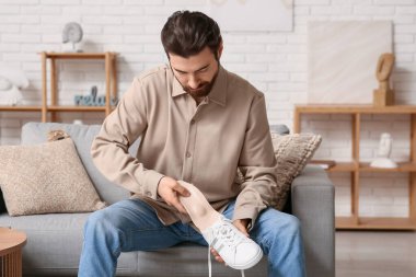 Genç adam evdeki spor ayakkabısına bej ortopedik taban takıyor.