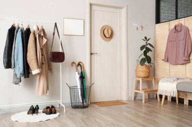 Beyaz duvarda elbise askısı, şemsiye ve anahtar tutacağı olan şık bir salon.