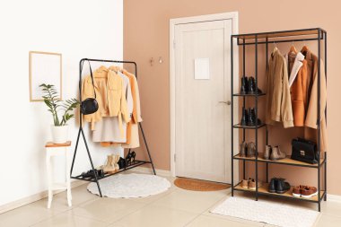 Raflar, elbise askıları ve anahtarlar bej duvarda asılı olan şık bir salonun içinde.