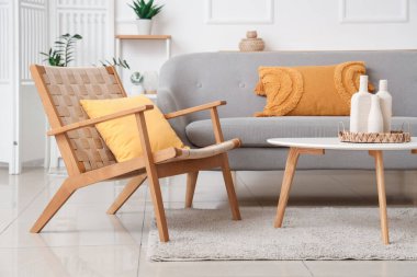 Şık, ahşap koltuklu, gri kanepeli ve sehpalı bir oturma odası.