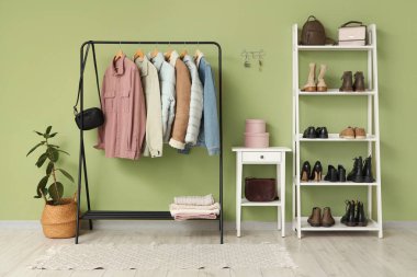 Elbise askısı, ayakkabı standı, tuvalet masası ve anahtar taşıyıcısı yeşil duvarlı şık bir salon.