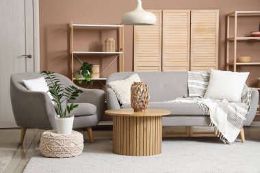 Şık bir oturma odası, rahat gri koltuğu, kanepesi ve ahşap kahve masası var.