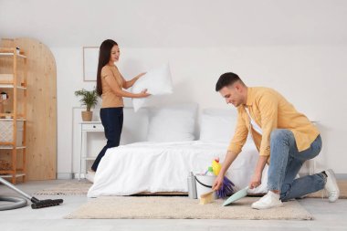 Genç ve şirin bir çift yatak odasını temizliyor.