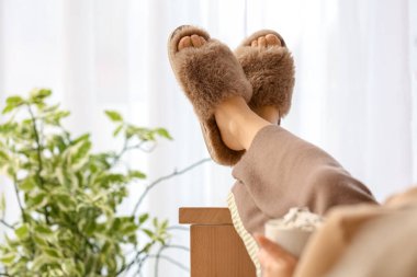 Oturma odasındaki kanepede dinlenen bir fincan kakaolu genç kadın.