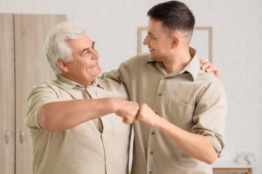 Babası evde yumruk tokuşturan genç bir adam.