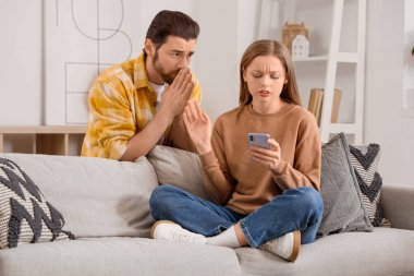 Genç adam evinde cep telefonuyla karısından özür diliyor.