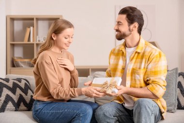 Hediyesi olan genç bir adam evinde karısından özür diliyor.