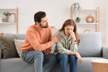 Genç adam evdeki kanepede ağlayan karısından özür diliyor.