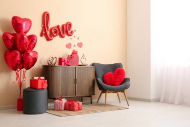 Gri koltuğu, hediye kutuları ve kalp şeklinde balonları olan şık bir oturma odası. Sevgililer Günü kutlaması