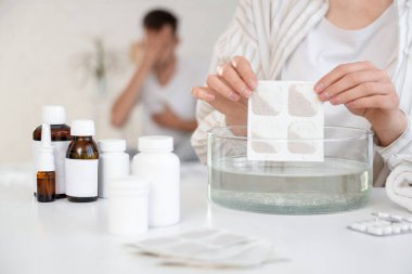 Yatak odasında hasta kocası için hardal bandıran genç bir kadın, yakın plan.