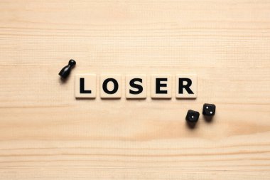 Hafif ahşap zemin üzerinde figür ve oyun küpleriyle Kelime Kaybeden