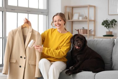 Evdeki kanepede pamuklu paltosu ve Labrador köpeği olan genç bir kadın.