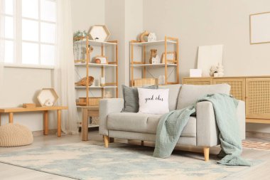 Gri kanepe ve raf üniteleriyle aydınlık oturma odasının içinde.