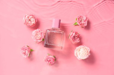 Bir şişe parfüm ve güzel pembe güller.