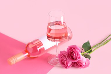 Bir bardak pembe şarap ve arka planda güzel güller.