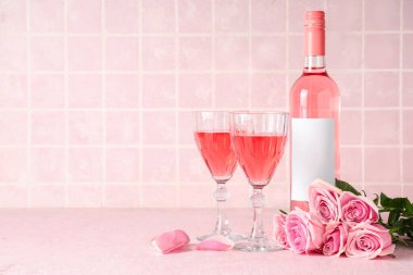 Bardaklar ve bir şişe pembe şarap. Masanın üzerinde güzel güller var.