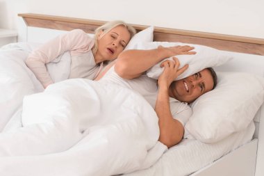 Kızgın olgun bir adam, horlayan karısıyla yatak odasında yatıyor.