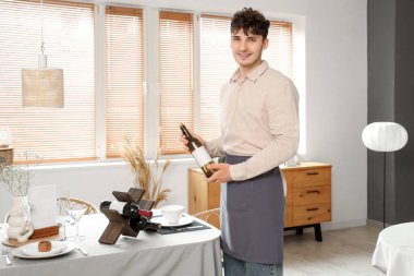 Restoranda elinde şarap şişesi olan bir erkek garson.