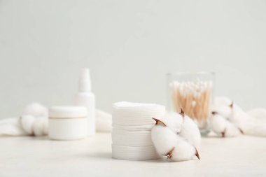 Kozmetik pedler, bezler, kozmetik ürünleri ve pamuk çiçekleri ışık masasında.