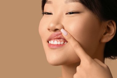 Bej arka planda sakız çiğnedikten sonra hassas dişleri ve diş etleri olan güzel bir Asyalı kadın. Yakın plan.