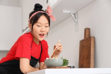 Lezzetli tofu ve sebzeli genç Asyalı kadın mutfaktaki kasede.